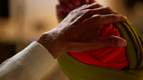 Close-Up-Studio-Shot-Of-Senior-Sikh-Man-With-Beard-Tying-Fabric-For-Turban-Viewed-From-Behind-Shot-In-Real-Time